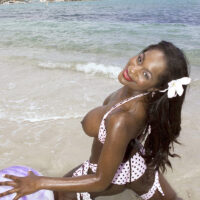 Black MILF Nikki Jaye extracts her enlargened tits from her bikini top while on a beach